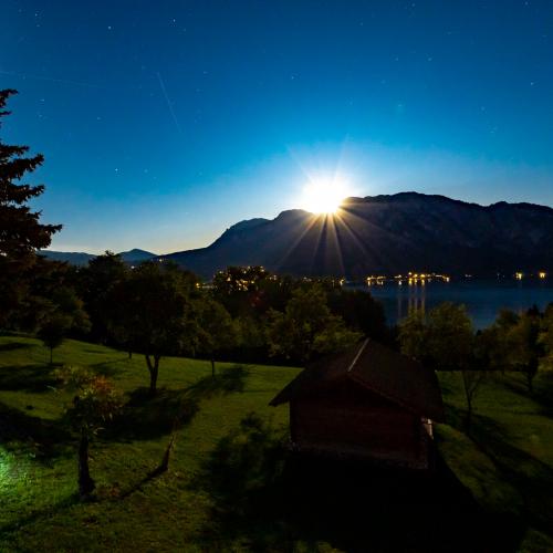 Long exposure of the moon rising behind the Alps on the Attersee in a summer night with stars and blue sky