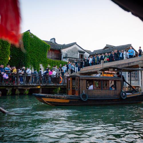 Crowd on the streets of Wuzhen seen from a traditional boat on the canal